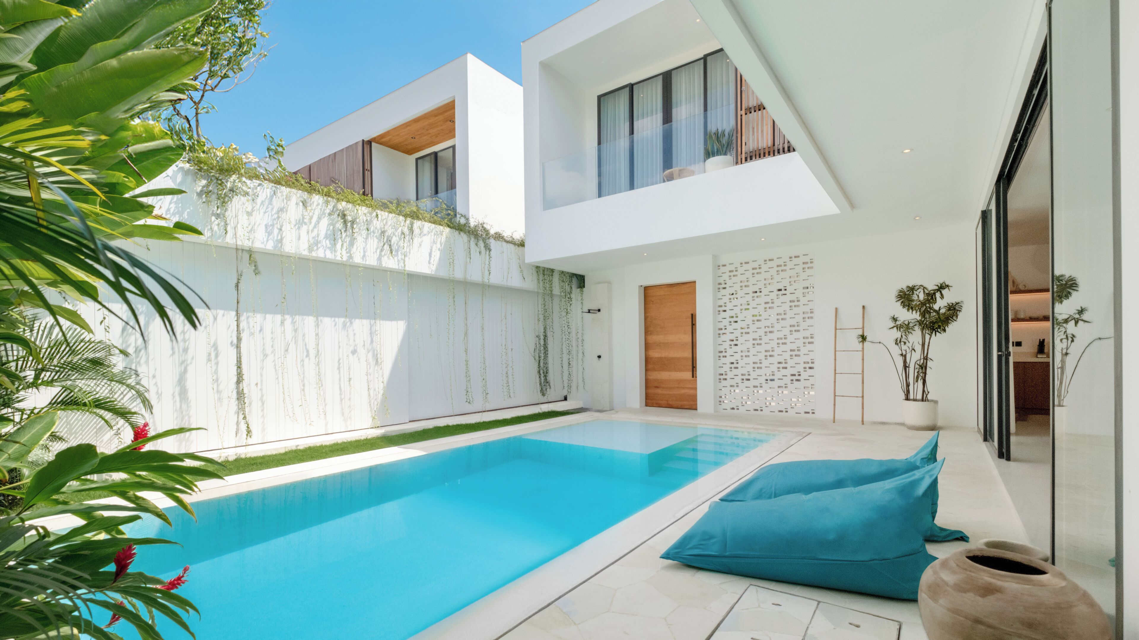 A modern house with a swimming pool, a wooden door, and a balcony.
