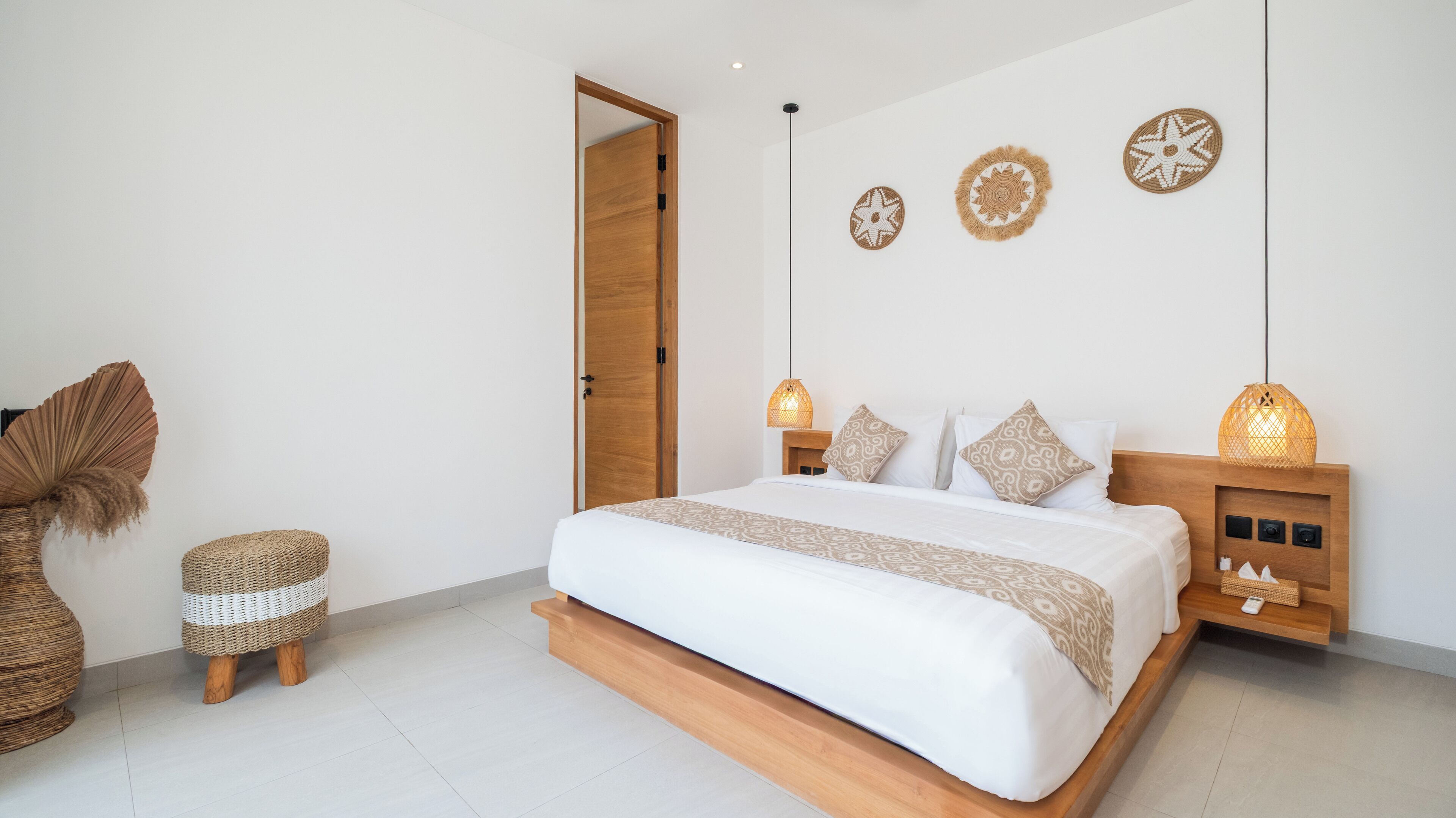 A modern bedroom with a wooden bed, bedside lamps, and woven decor.