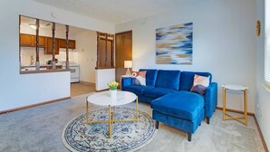 Un salon avec un canapé bleu, une table basse ronde et un tapis.