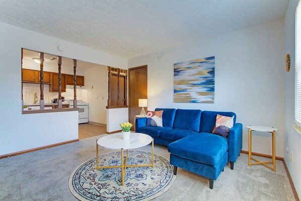 A living room with a blue sofa, a round coffee table, and a rug.