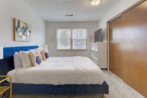 Une chambre à coucher avec un lit, une armoire, une télévision et une fenêtre.