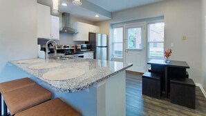 Een moderne keuken met granieten aanrechtbladen, roestvrijstalen apparatuur en een centraal eiland met zitplaatsen.