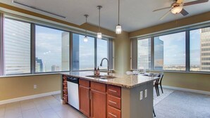 Una cocina moderna con una isla central, ventanas amplias y un ventilador de techo.