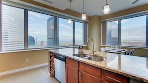 Una cocina moderna con una isla grande, electrodomésticos de acero inoxidable y ventanas amplias con vistas a la ciudad.