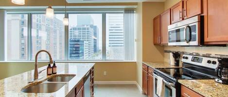A modern kitchen with granite countertops, stainless steel appliances, and wooden cabinets.