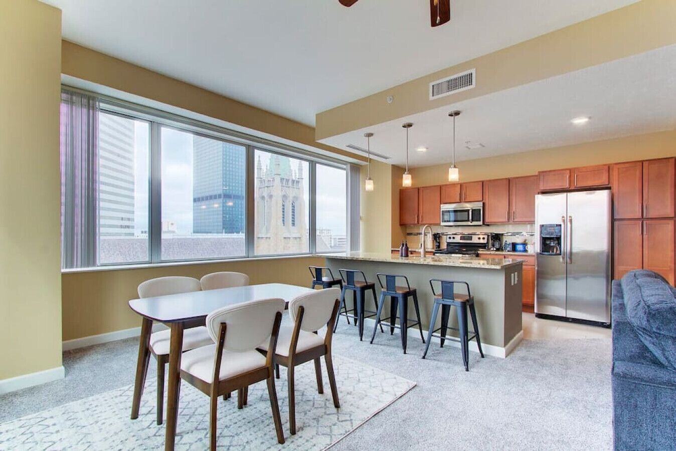A modern kitchen with a central island, wooden cabinets, and a stainless steel refrigerator.