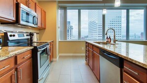 A modern kitchen with a large window, stainless steel appliances, and a city view. - Luxury High Rise | Downtown | Free Parking (Cleveland)