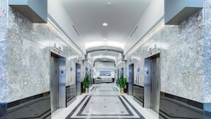 A modern hotel lobby with marble walls, a central tiled area, and elevators on either side. - Luxury High Rise | Downtown | Free Parking (Cleveland)