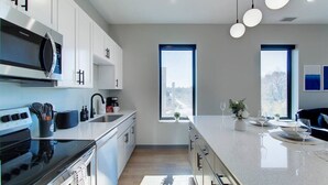 Una cocina moderna con armarios blancos, una estufa negra y un amplio ventanal con vistas a la ciudad.