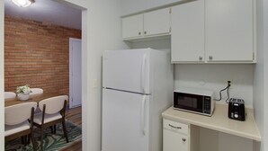 Eine kleine Küche mit Kühlschrank, Mikrowelle und Toaster. Ein Essbereich mit Tisch und Stühlen ist ebenfalls vorhanden.