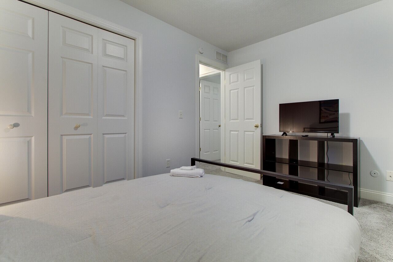 A bedroom with a bed, a television on a stand, and a wardrobe.