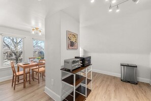 Een moderne keuken met een eetgedeelte, een magnetron en een prullenbak.