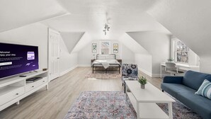 Une chambre de style loft moderne, dotée d’une grande télévision, d’un lit, d’un bureau et d’un canapé.