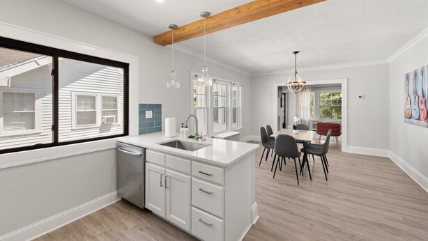 A modern kitchen with white cabinetry, a large island, and pendant lighting. - 2BR Near Cleveland Clinic | Garage & Patio (Cleveland Heights)