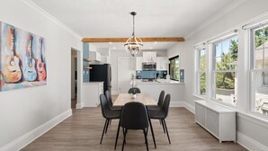 A dining area with a wooden table and chairs, a chandelier, and a painting of guitars on the wall. - 2BR Near Cleveland Clinic | Garage & Patio (Cleveland Heights)