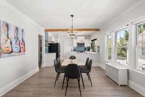 A dining area with a wooden table and chairs, a chandelier, and a painting of guitars on the wall. - Bright & Peaceful | 2BDR w/ Patio | CLE Clinic (Cleveland Heights)