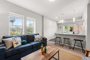 Un salon moderne avec un canapé, une table basse et des tabourets de bar.