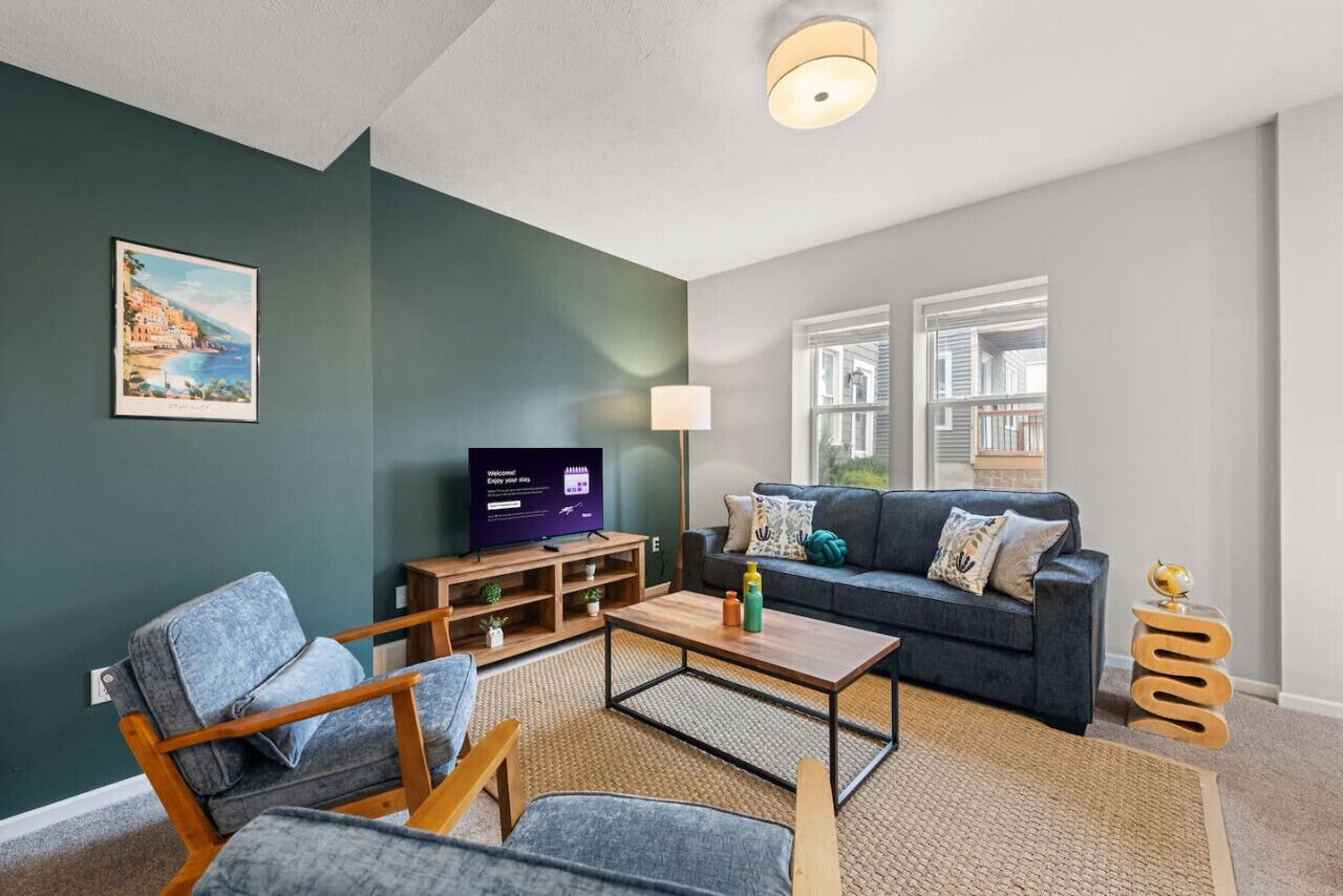 Un salon moderne avec un mur vert foncé, un canapé, une table basse et un téléviseur.