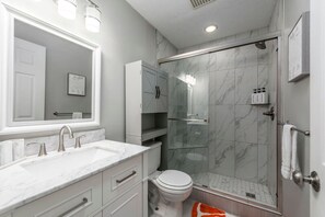 Un baño moderno con lavamanos doble, inodoro, cabina de ducha de vidrio y un espejo grande.