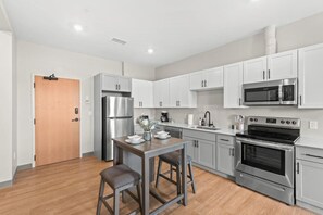 Enjoy cooking in this well-equipped kitchen with stainless steel appliances, white cabinetry, and a dining table for two.