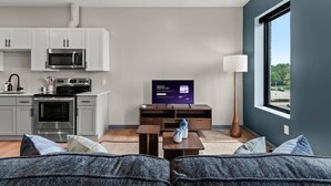 A modern living room with a sofa, a coffee table, and a flat-screen TV.