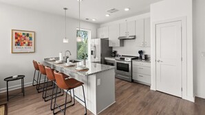 A modern kitchen with a central island, stainless steel appliances, and a bar area with stools. - Gorgeous 2 Bed/2 Bath | CLE Clinic | Balcony (Cleveland)