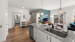 A modern kitchen with granite countertops, a stainless steel sink, and a dining area with a table and chairs. - Gorgeous 2 Bed/2 Bath | CLE Clinic | Balcony (Cleveland)