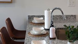 A kitchen with a granite countertop, a sink, a faucet, and a vase with a plant. - Gorgeous 2 Bed/2 Bath | CLE Clinic | Balcony (Cleveland)