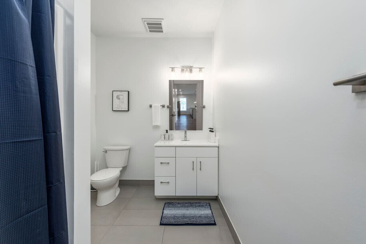 Et badeværelse med toilet, håndvask og spejl.
