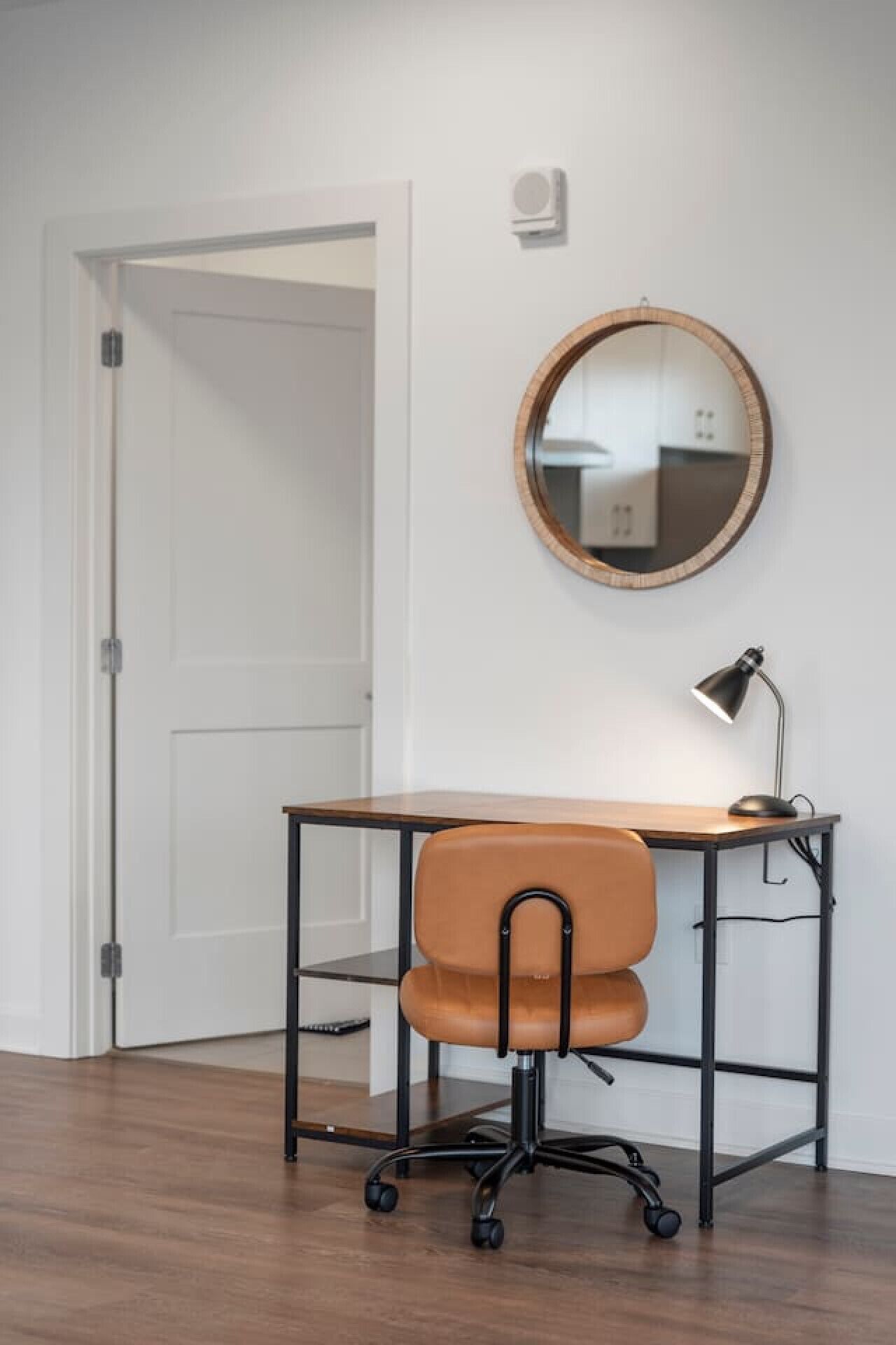 Un espace de travail comprenant un bureau, une chaise et un miroir fixé au mur.