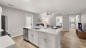A modern kitchen with white cabinetry, a dishwasher, a refrigerator, and a ceiling fan.
