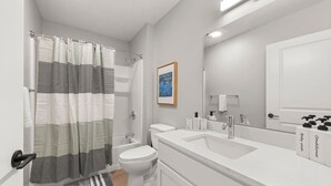 A modern bathroom with a shower curtain, toilet, sink, and mirror.