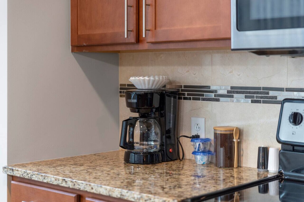 A kitchen with a coffee maker, a microwave, and a tiled backsplash.