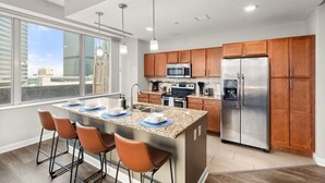 Una cocina moderna con una isla grande, electrodomésticos de acero inoxidable y vistas a la ciudad.