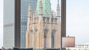 Habitación de hotel con cama, almohadas, lámpara y vista a un edificio histórico.