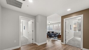A spacious hallway with hardwood flooring, white walls, and a ceiling fan.