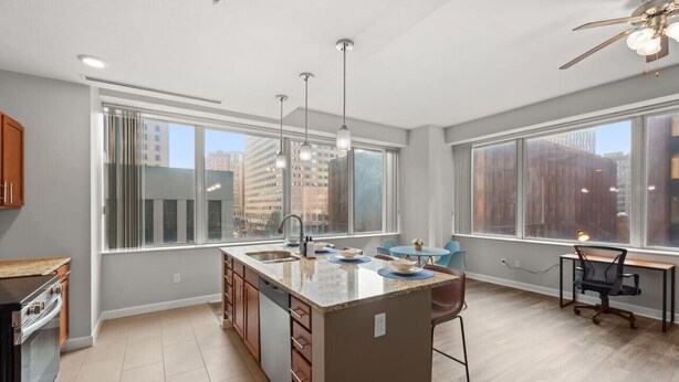 A modern kitchen with a central island, large windows, and a dining area with a view.