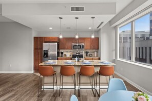 Cozinha moderna com ilha central, banquetas e iluminação pendente.