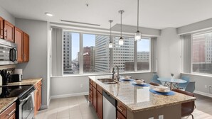 A modern kitchen with a large island, built-in oven, and microwave.