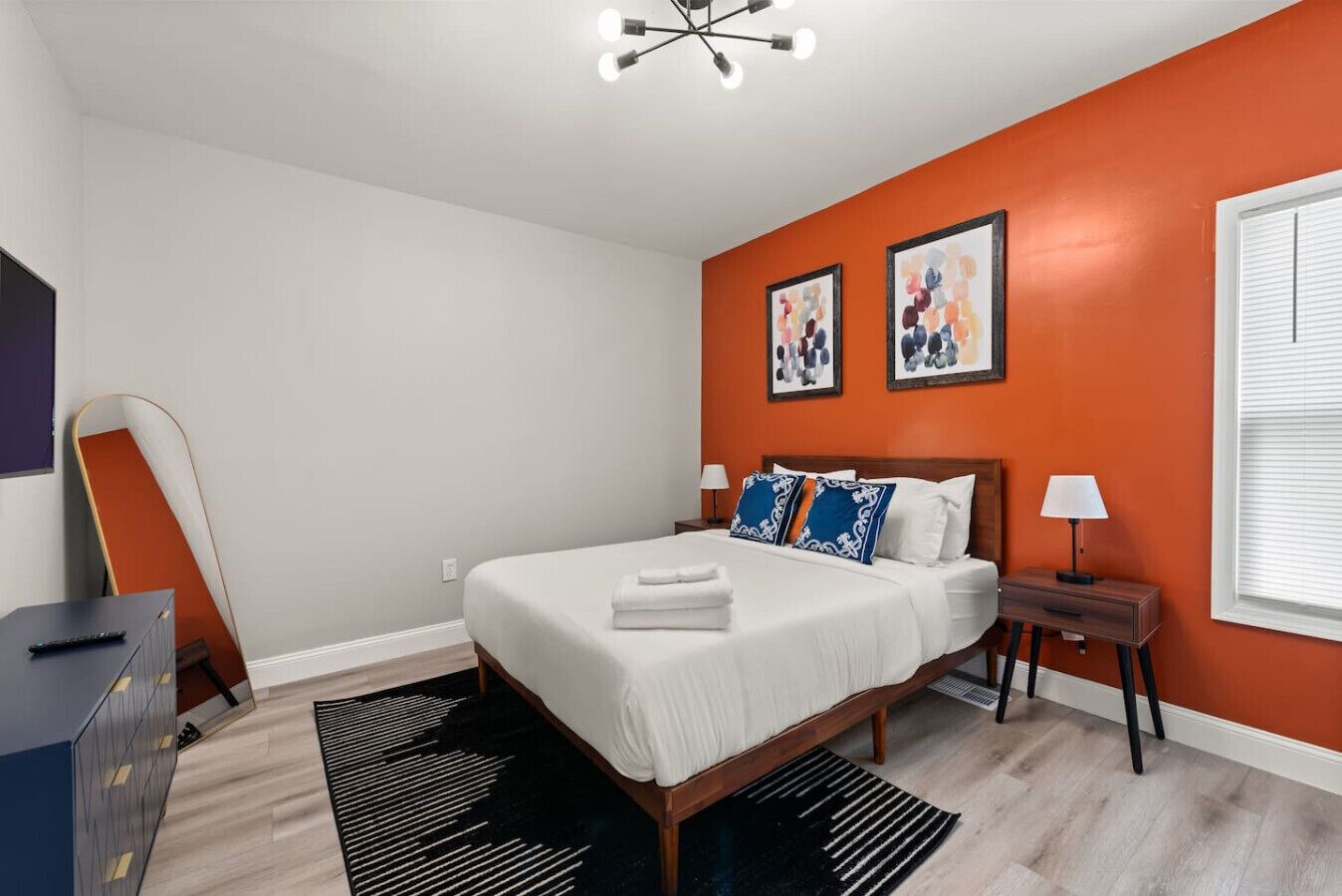 A bedroom with a bed, a nightstand, a lamp, a dresser, and a chair.