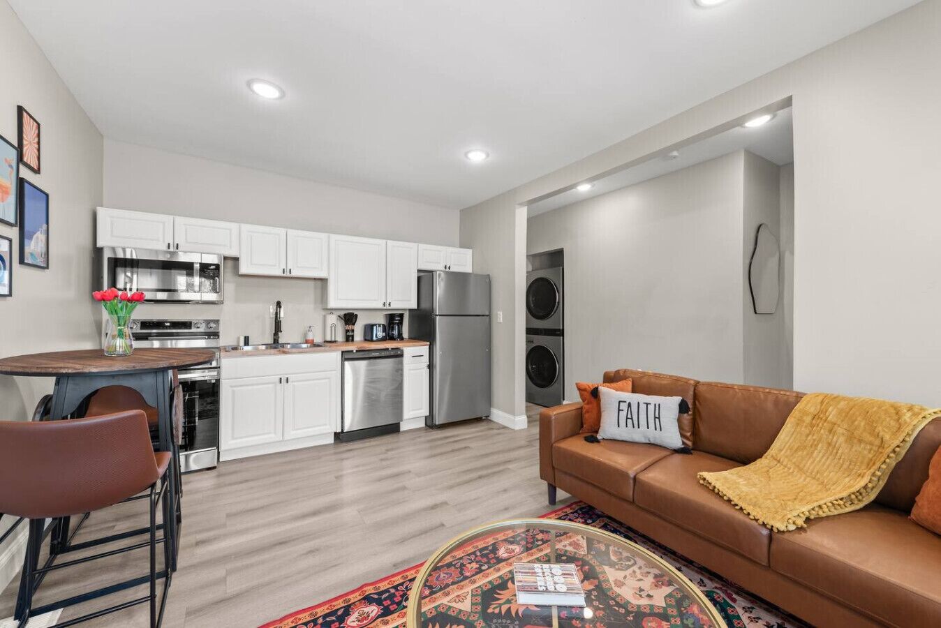 A modern kitchen with white cabinets, stainless steel appliances, and a dining area with a round table and chairs.