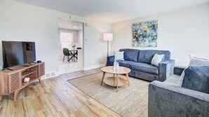 A living room with a TV, sofa, coffee table, and a painting on the wall.