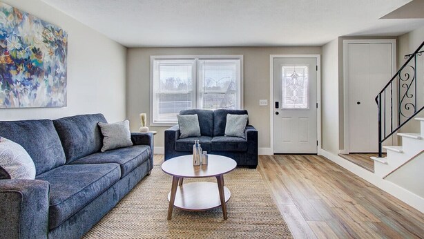 A living room with a sofa, a coffee table, and a staircase.