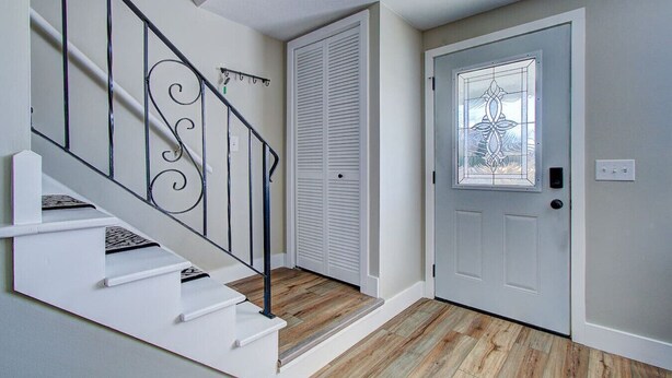 A staircase with a metal railing, a white door with a glass panel, and a wooden floor. - Cozy 2BR with Garage | Central North Canton (North Canton)