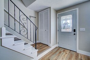 A staircase with a metal railing, a white door with a glass panel, and a wooden floor.