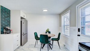 A compact kitchen with a dining area, white cabinetry, a marble floor, and a green plant on the table. - Cozy 2BR with Garage | Central North Canton (North Canton)