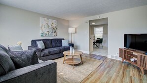 A living room with a sofa set, a coffee table, a TV, and a painting on the wall. - Cozy 2BR with Garage | Central North Canton (North Canton)