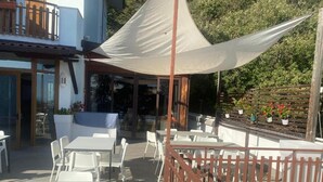 An outdoor patio with white tables and chairs, a wooden fence, and a large white canopy. - BikeHotel Abete (San Giovanni Rotondo)