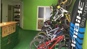 A room with green walls, a wooden counter, and multiple bicycles. - BikeHotel Abete (San Giovanni Rotondo)
