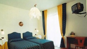 A room with two beds, a desk, a television, and a window with curtains. - BikeHotel Abete (San Giovanni Rotondo)